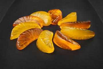 Jelly citrus candy on a black dish on a dark background.