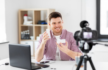 blogging, videoblog and people concept - male blogger with box and camera recording video at home office