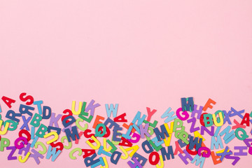 Letras de abecedario con letras de colores vista desde arriba sobre fondo rosa. Copy space