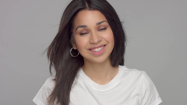 happy smiling mixed race woman with blowing straight brunette hair watching to the camera and smiling