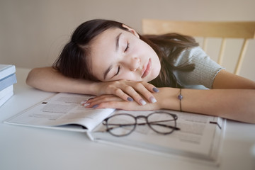Cute teenager girl fell asleep on the books when she did her homework   