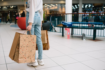 Shopping time, closeup of teenage girl legs with shopping bags at shopping mall