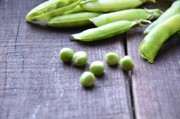 fresh green peas, just harvest. close up view of opened pod. spring vegetable up view on the wooden background