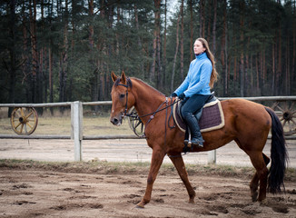 young woman riding red don mare horse in spring landscape