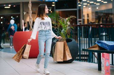 retail, gesture and sale concept - smiling teenage girl with many shopping bags at mall