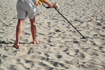 Man with a metal detector on a sea sandy beach in summer day