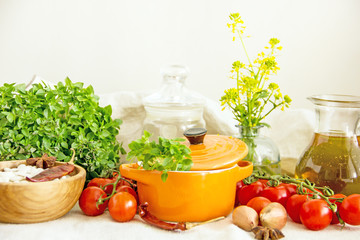 Food and utensils to prepare food. Fresh basil, cherry tomatoes, beans, olive oil, lime, onion, spices, saucepan, jars in cereals. Culinary background. Copy space