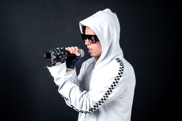 Karaoke man sings a song into a microphone, on a dark concrete background. A funny man holds a microphone in his hand at a karaoke singer singing a song! Pivets against dark background