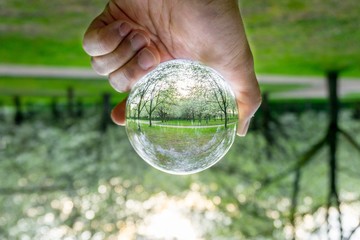 A hand holding a crystal ball for optical illusion. Known as an orbuculum, is a crystal or glass ball and common fortune telling object. Performance of clairvoyance and scrying