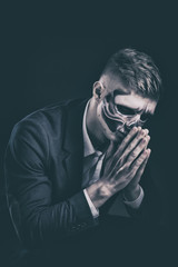 Stylish and beautiful, emotional young man with skeleton makeup in a strict suit against the background of smoke and dark background to Halloween