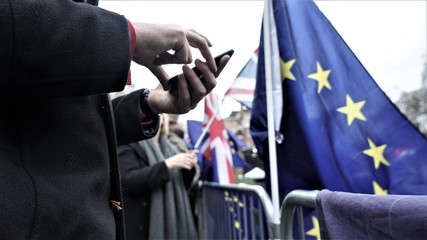 Man holding a phone next to an EU flag during Brexit protest and EU elections. 