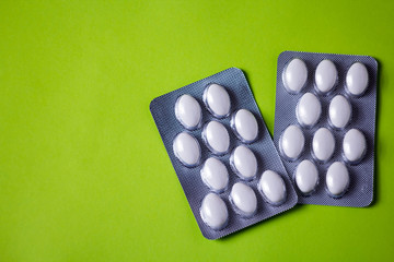 blister with white pills on green background with copyspase