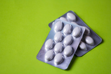 blister with white pills on green background with copyspase