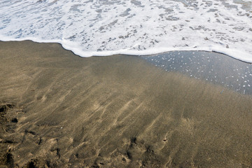 Beautiful soft wave on black sand at the sea