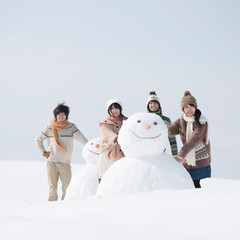 雪だるまの周りで微笑む大学生