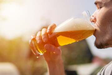 A man drinks beer from a glass in the heat