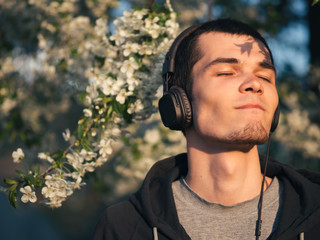 A young man enjoys listening to music in headphones in nature