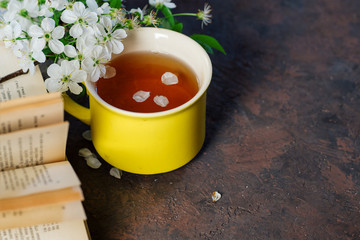 A Cup of green spring tea . Cherry blossoms and a book on the table with copy space