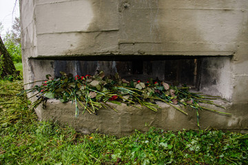 The embrasure of the bunker is stacked with flowers of memory. Reconstruction of the battle. Defensive bunker number 401 near Kiev. The line of defense of July 1941 Ukraine. June 23rd, 2019