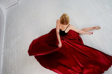 A gymnast in a dark top and a red silk skirt. The color of passion, of aggression. Tango. Plastic...