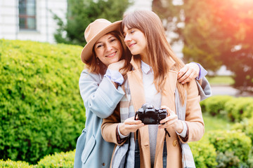 Outdoor portraits of two pretty sisters women friends taking selfie on camera, enjoy nice day, looking on camera and making funny faces over spring park background.Sun glare.Travel, lifestyle concept.