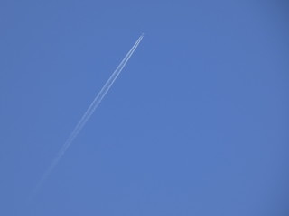 avión surcando el cielo azul y dejando una estela de color blanco
