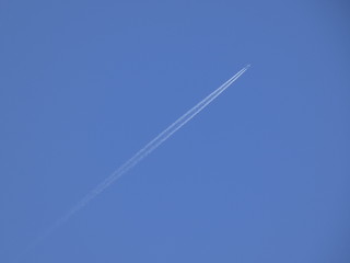 Avión surcando un cielo azul y dejando una estela blanca a su paso