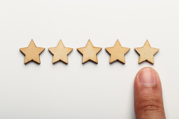 Hand pointing wooden five star shape on white background