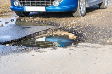 Car and winter pothole on open road