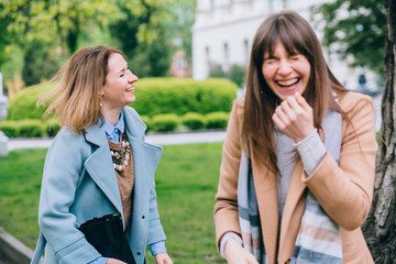 Two adult stylish best friends female sisters having fun, laughing after quarrel outdoor in the...