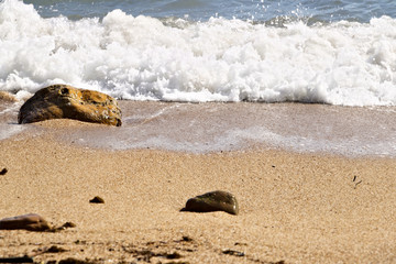 Sea waves break on the beach with stones.