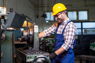 Turner worker is working on a lathe machine in a factory