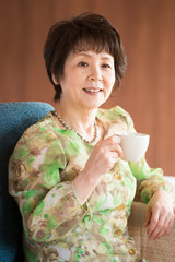 コーヒーカップを持ち微笑むシニア女性