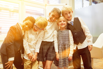 Lachende Gruppe Kinder als Business Team in Schule