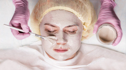 Cosmetologist applying facial mask to problem skin. young woman having skin procedures cleaning