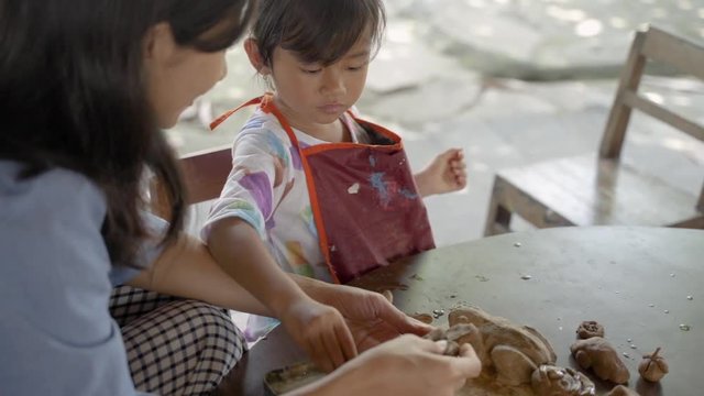 mother and daughter making ceramic pot in pottery workshop