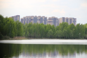 Fototapeta na wymiar New building, many apartments at home. Residential building in a public green Park is located next to the lake