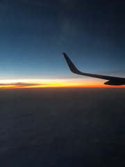 View from the wing of the aircraft in flight, the evening Golden light under the clouds.