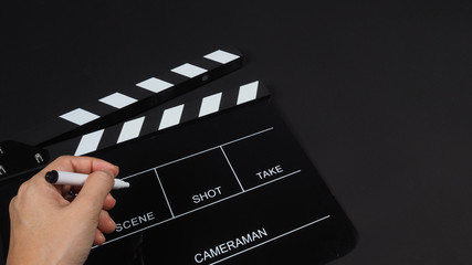 Fototapeta na wymiar Black Clapperboard or clap board or movie slate with hand holding pen use in video production ,film, cinema industry on black background.