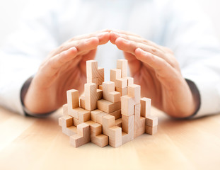 Safety business development concept. Wooden blocks covered by hands. 