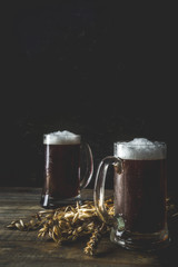 Two Homemade craft beer mugs, dark wooden background copy space