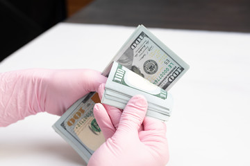 The woman counts the money dollars in pink gloves for sterility. White background.
