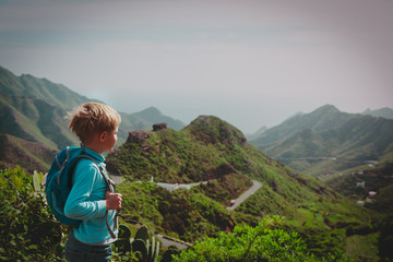 Naklejka premium little boy with backpack hiking in mountains