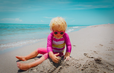 cute little girl play with sand on beach