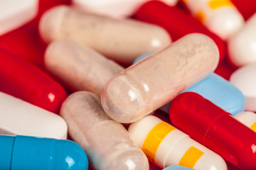 Many medicine pills close up on red background