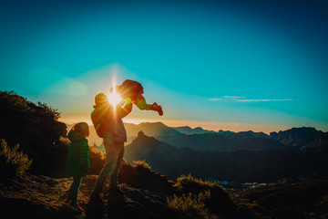 Father and kids enjoy travel in sunset mountains