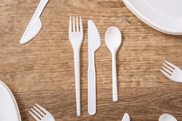 Disposable plastic cutlery on wooden table. Top view