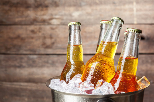 Cold bottles of beer in the bucket on the wooden background