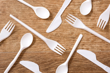 Disposable plastic cutlery on wooden table. Top view