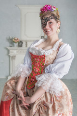 Beautiful woman in old-fashioned historic medieval dress with mask